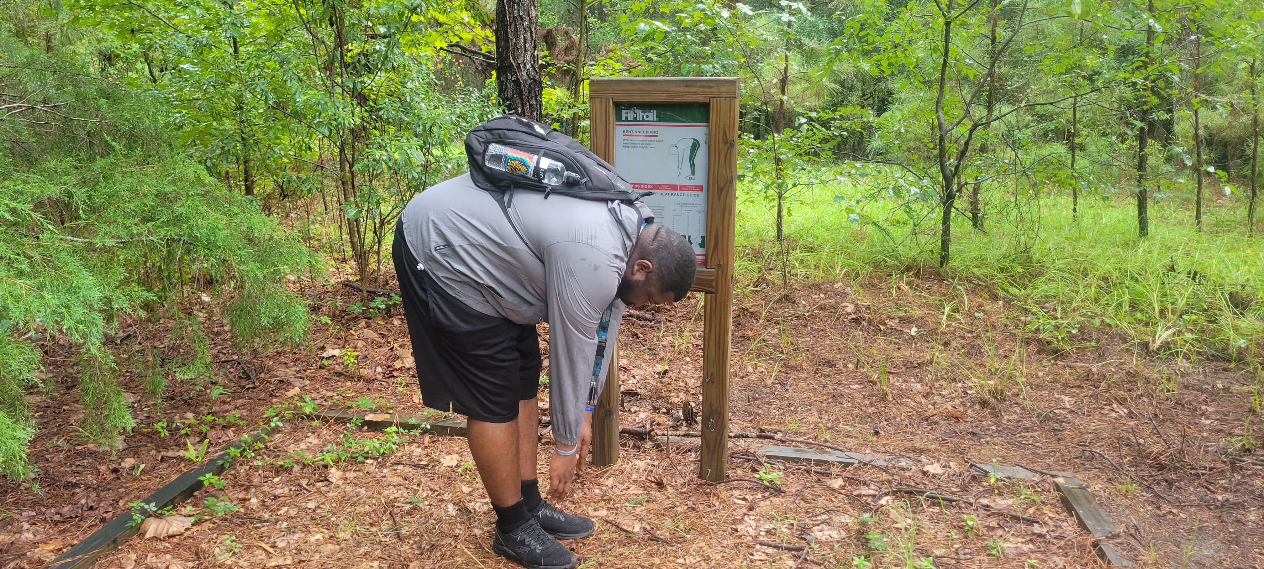man stretching by nature trail