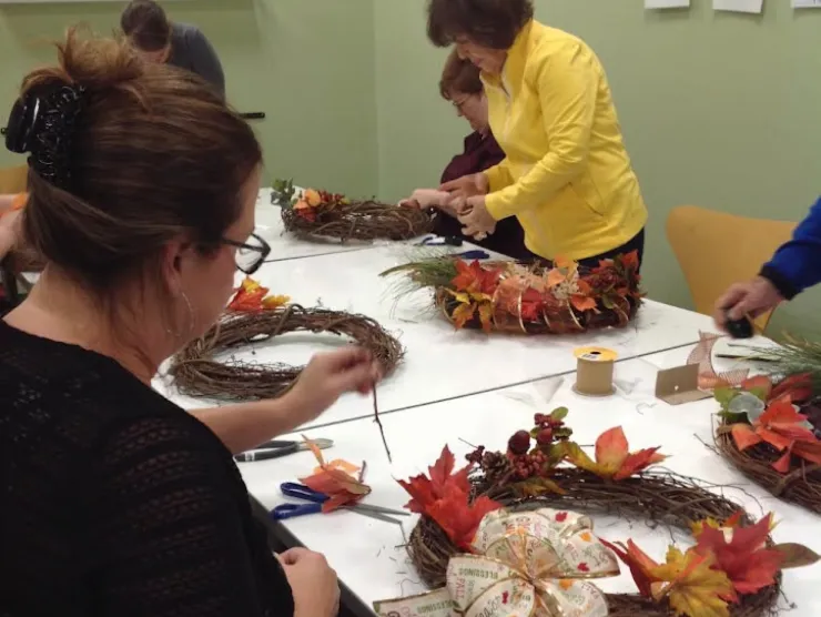 Women sitting around table making fall wreaths