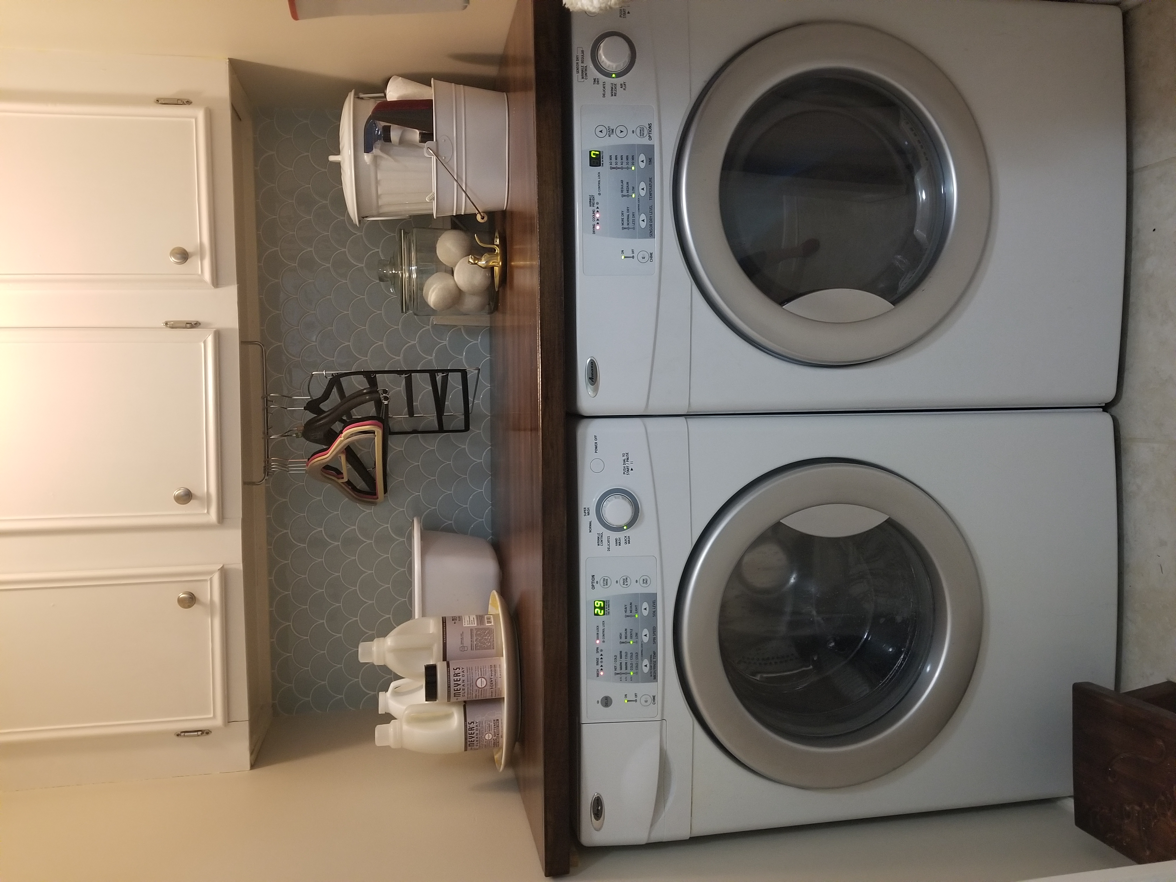 laundry closet with side-by-side washer and dryer, blue tile backsplash, and a dark wood countertop