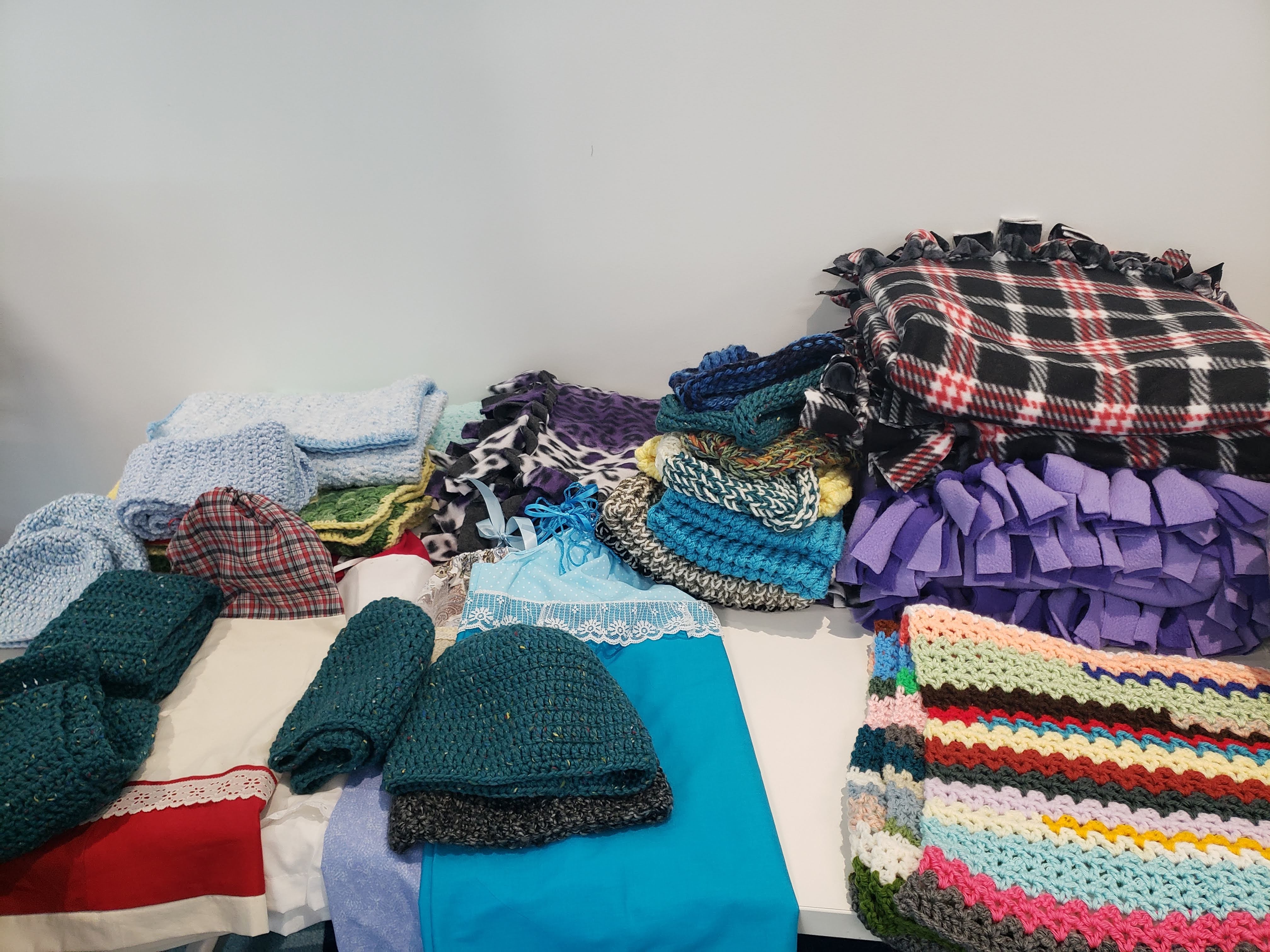 Crocheted, knitted and felted blankets; knitted hats and scarves; cloth children's dresses.