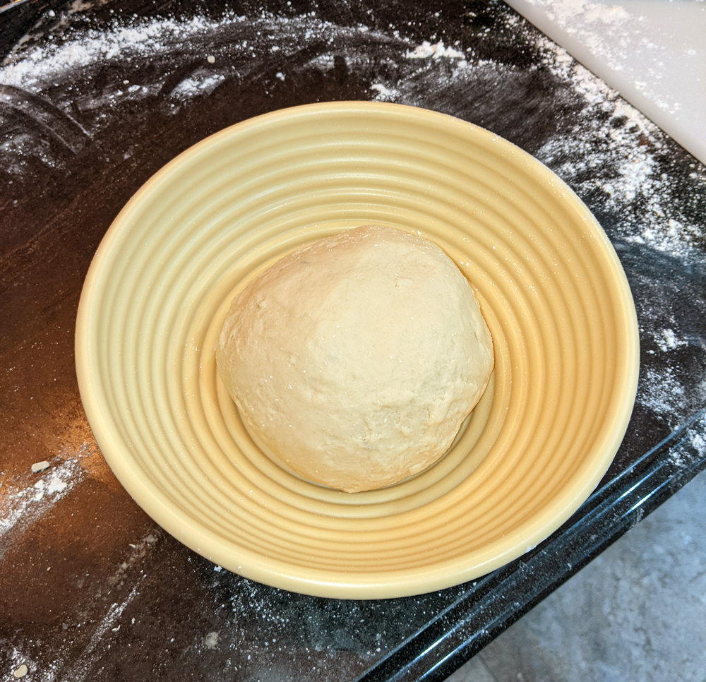 Photo: a ball of pale dough sitting in the bottom of a yellow ridged proofing bowl