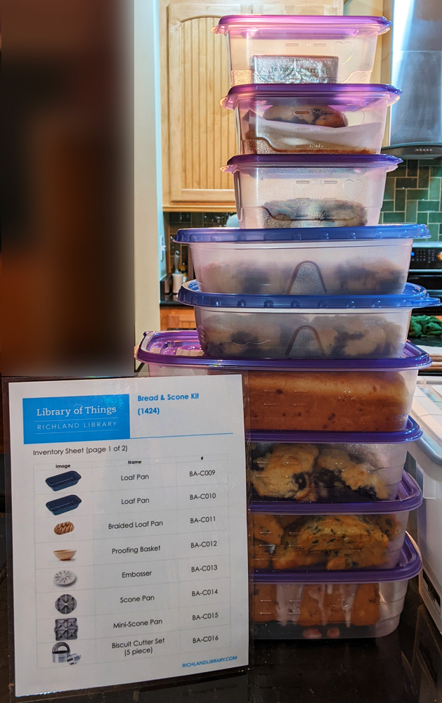 Photo: a laminated sheet detailing the contents of the Bread and Scone Kit, with a tall tower of to-go containers with all of the baked goods