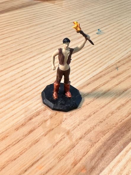 Painted miniature figurine holding a torch