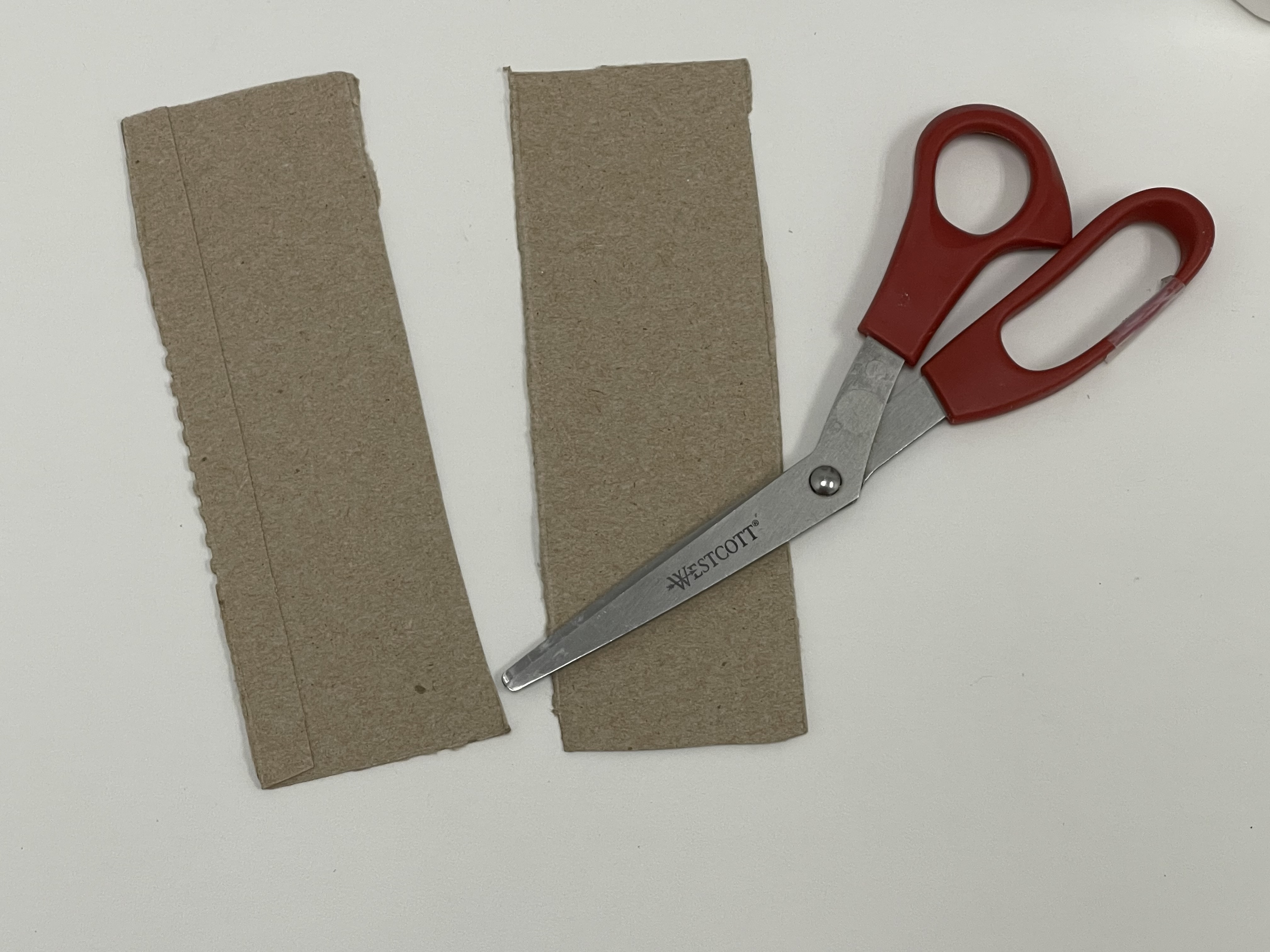 red handle scissors and two cardboard pieces