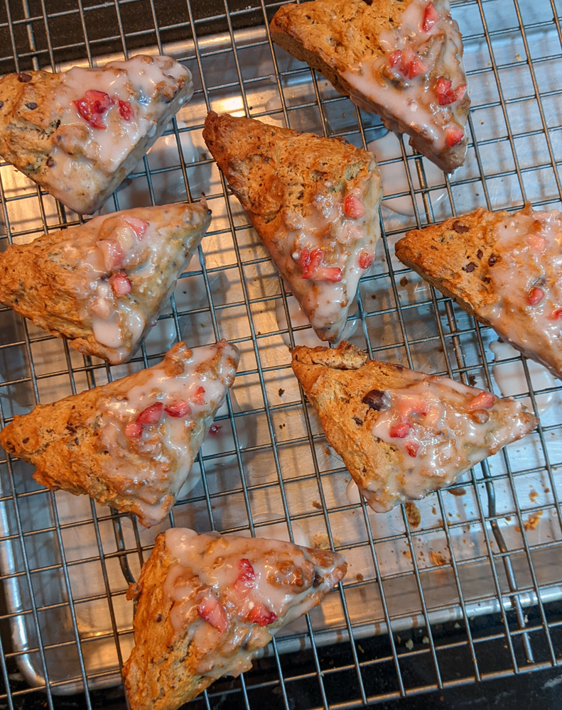 Photo: mini chocolate chip scones half dipped in a glaze with strawberry bits in it