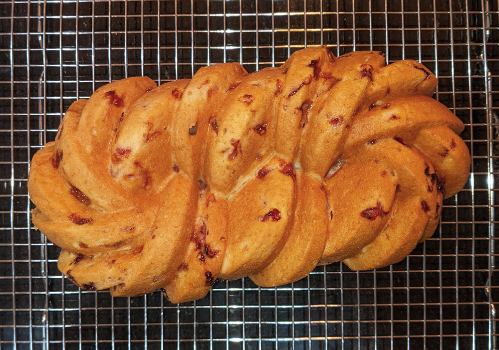 Photo: a loaf of strawberry bread baked in a braided loaf pan, all golden brown and crusty