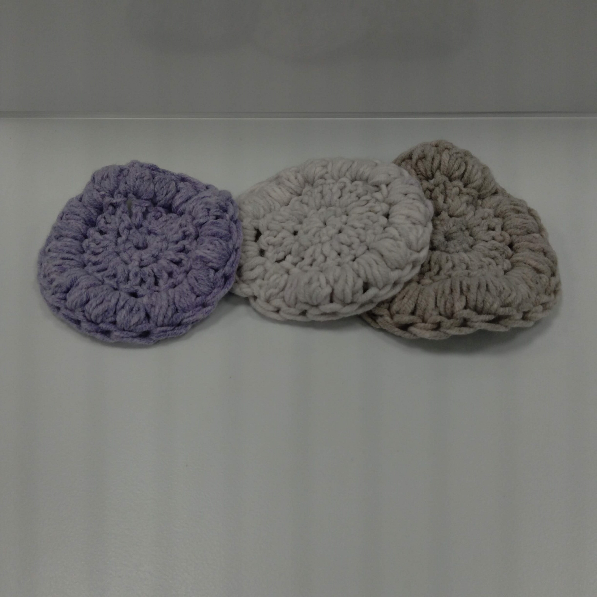three crocheted facial rounds in cream, beige and lavender