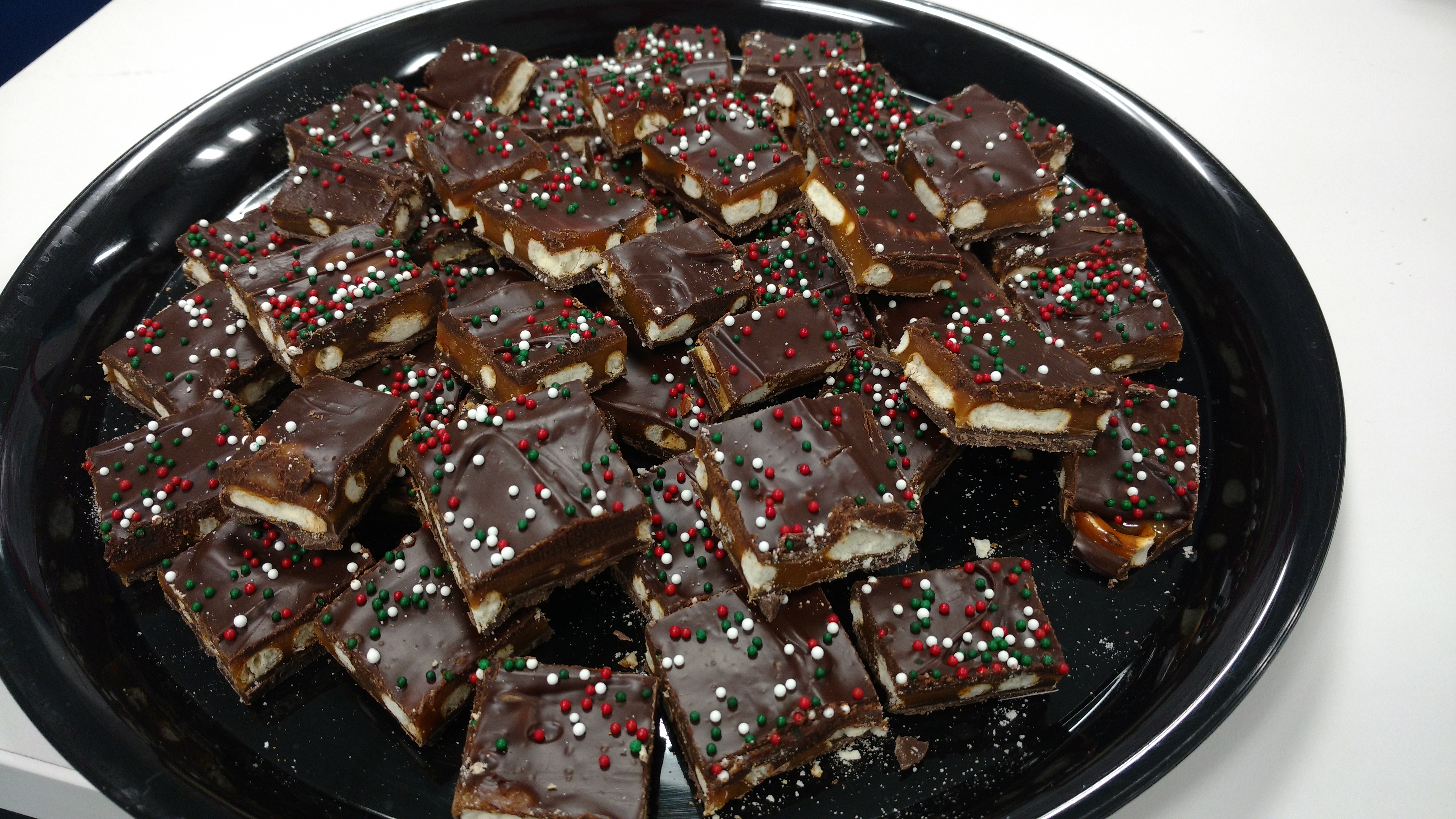 Tray of chocolate pretzel bark bites with red and green sprinkles