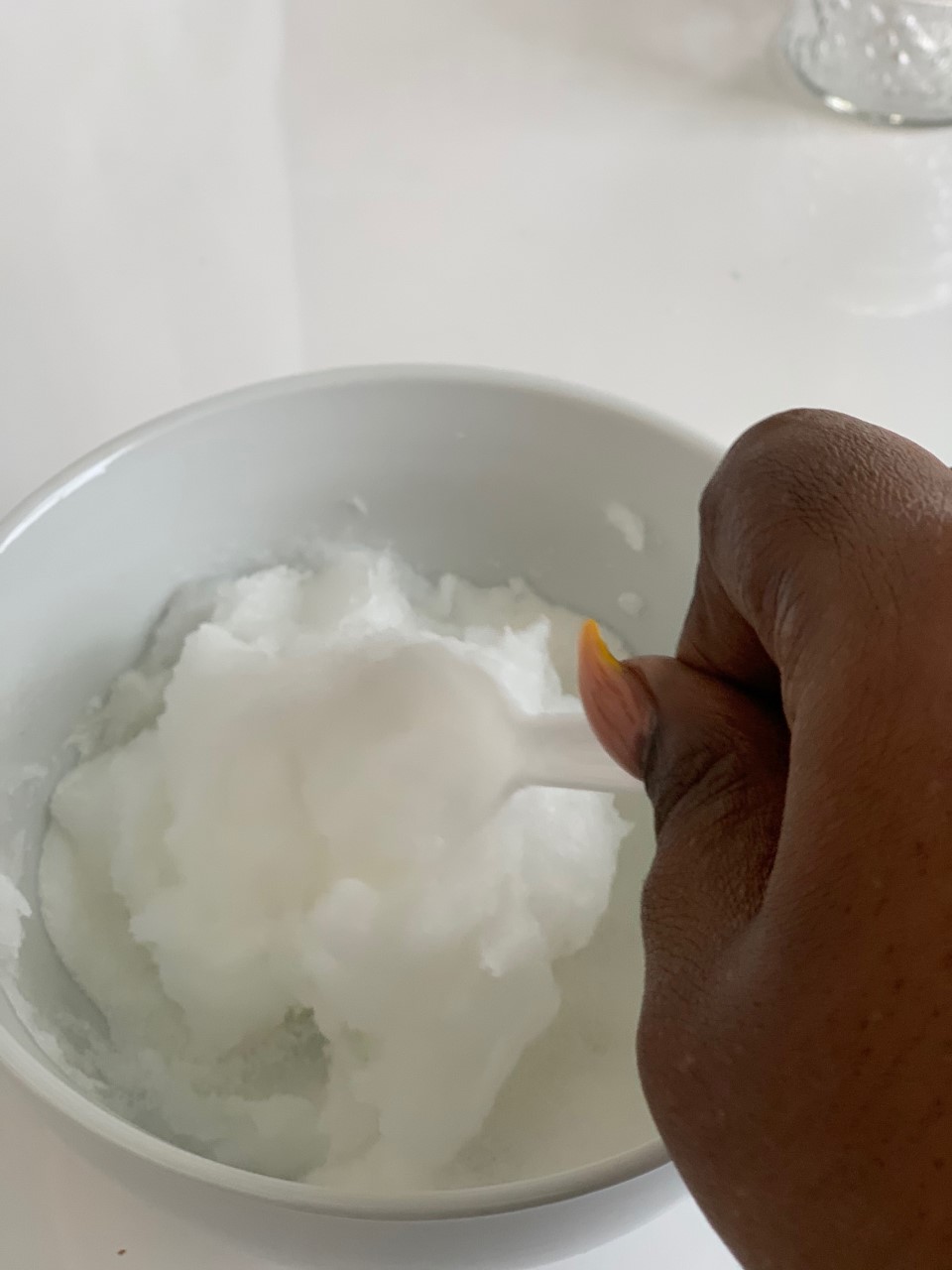Mixing sugar and coconut oil in glass bowl.
