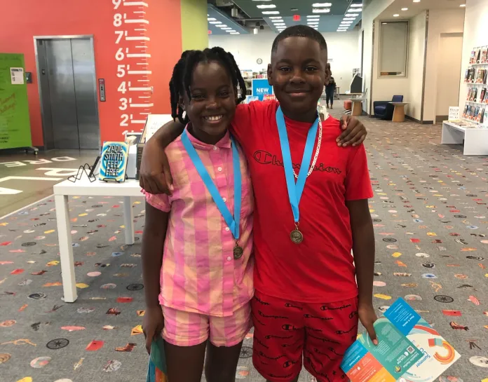 Two kids receiving summer learning completion coupons