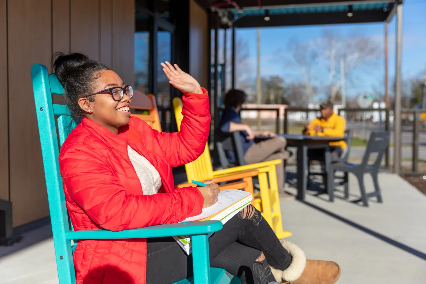 College student sits in bright blue rocking chair at Richland Library Edgewood Courtyard