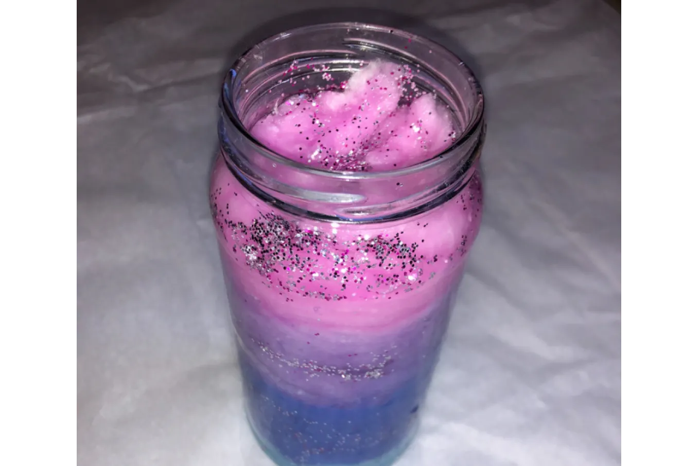 Mason Jar with different color cotton (pink, purple, periwinkle, and blue) and glitter (silver and purple) inside