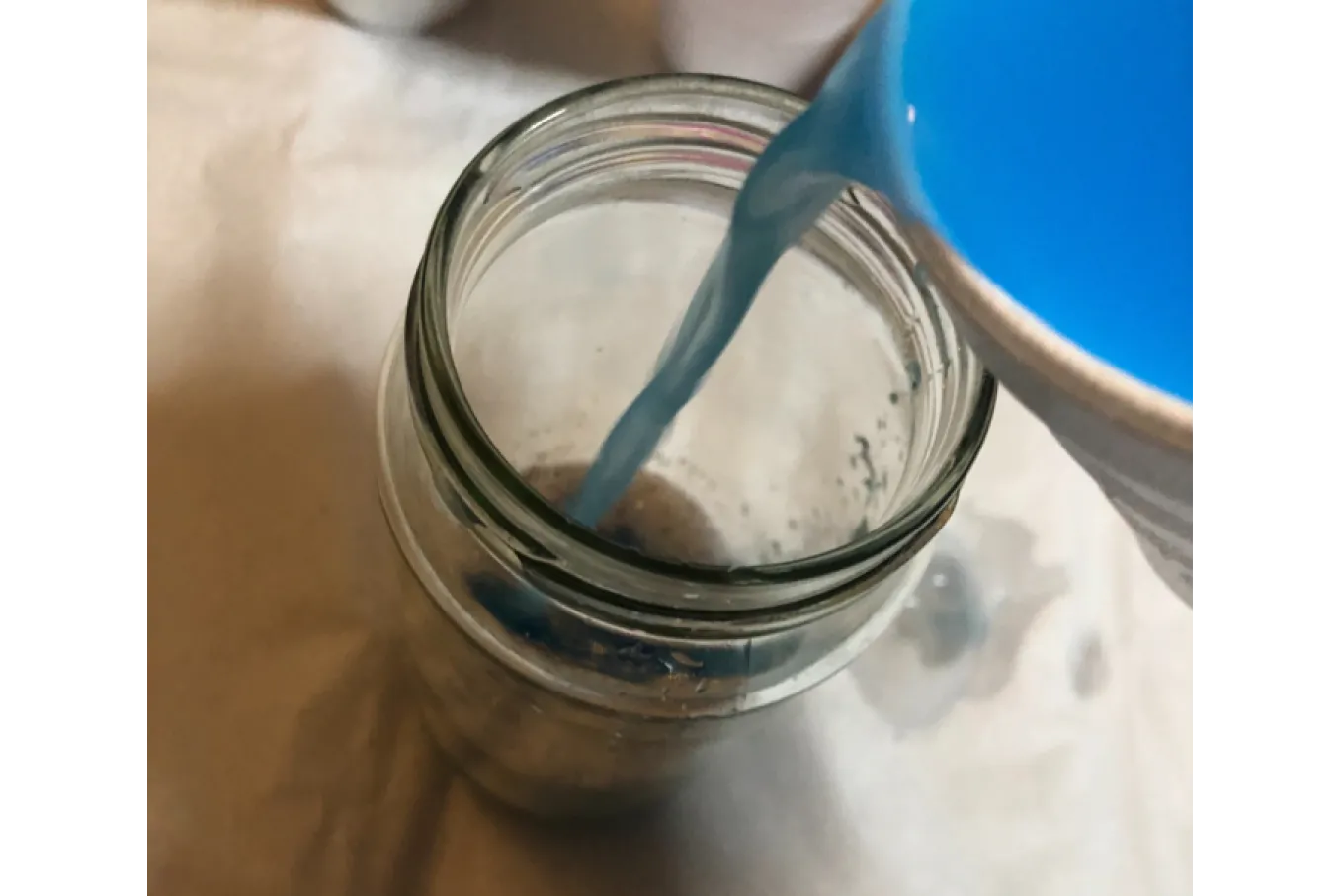 Blue Paint and Water mix being poured into mason jar 