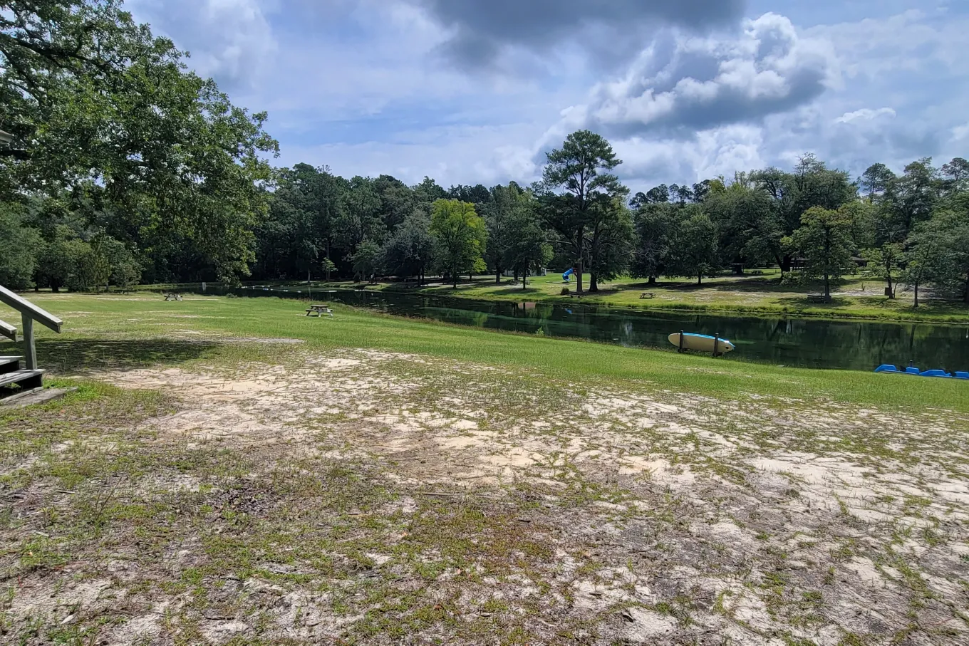 Field with dirt by a river and kayaks