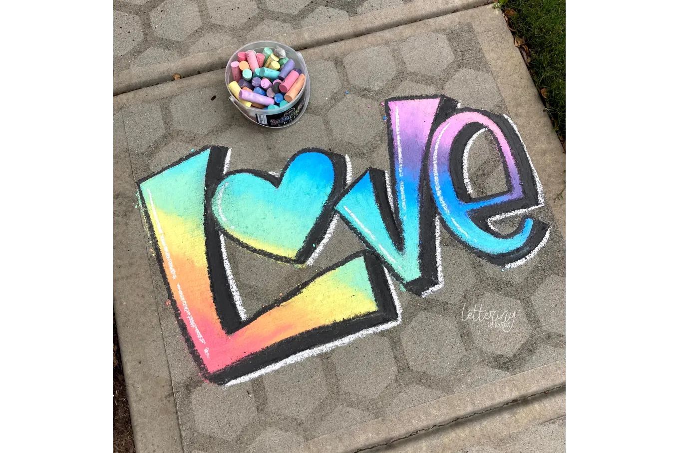 Chalk art of the word "LOVE" in rainbow gradient and black outline
