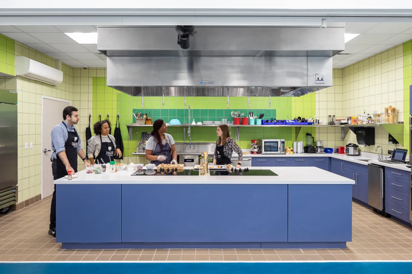 Group of Adults gather around the island in the teaching kitchen at Richland Library Northeast