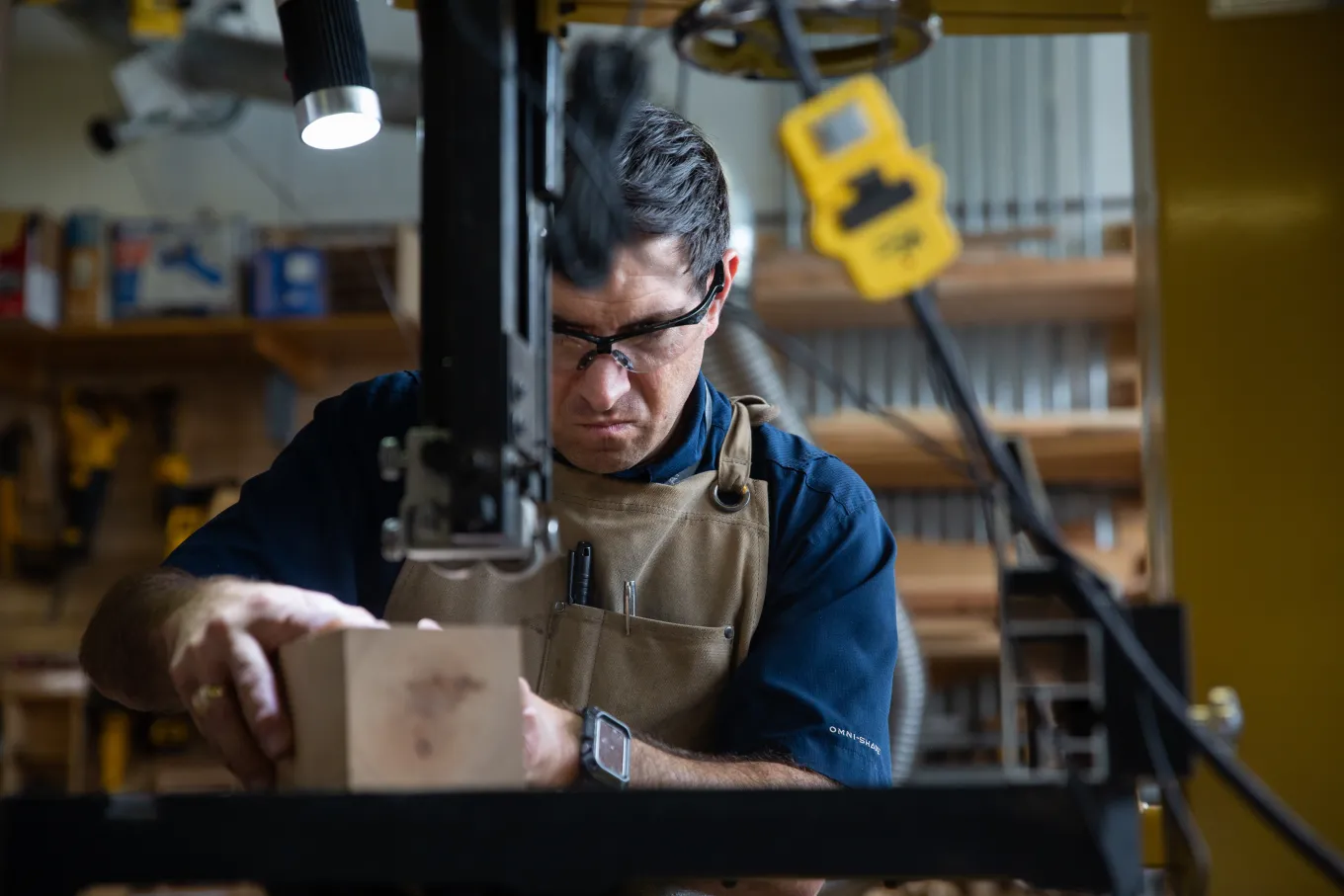 Male staff member cuts wood in Fabrication Studio