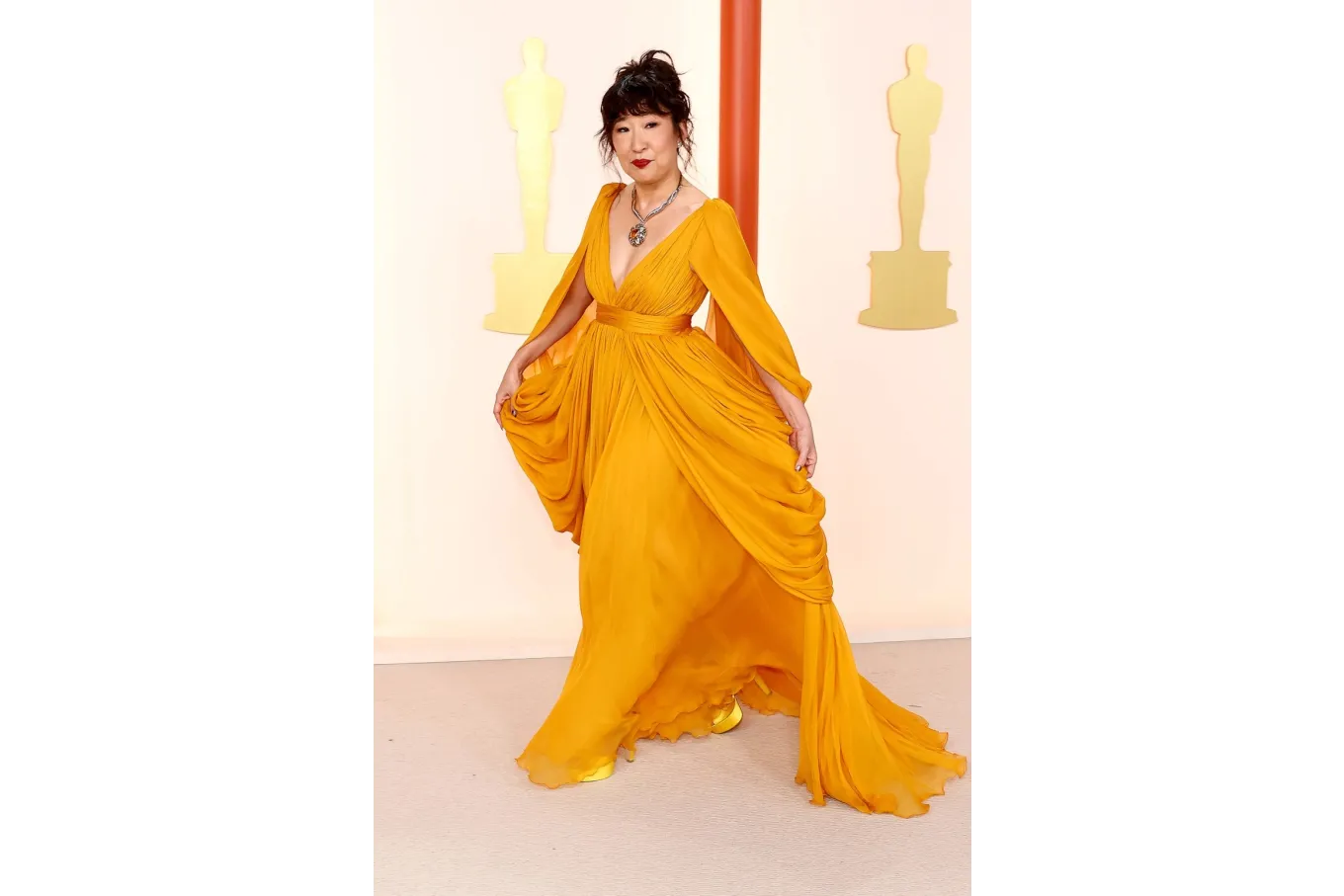actress Sandra Oh wearing a mustard-colored chiffon dress