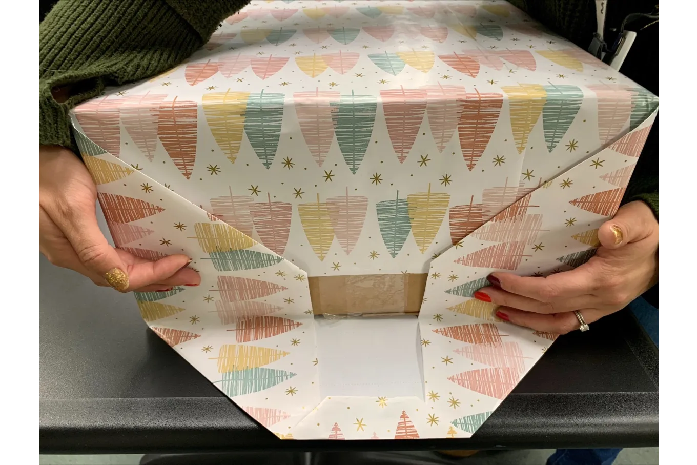 a box being wrapped in multicolored holiday wrapping paper