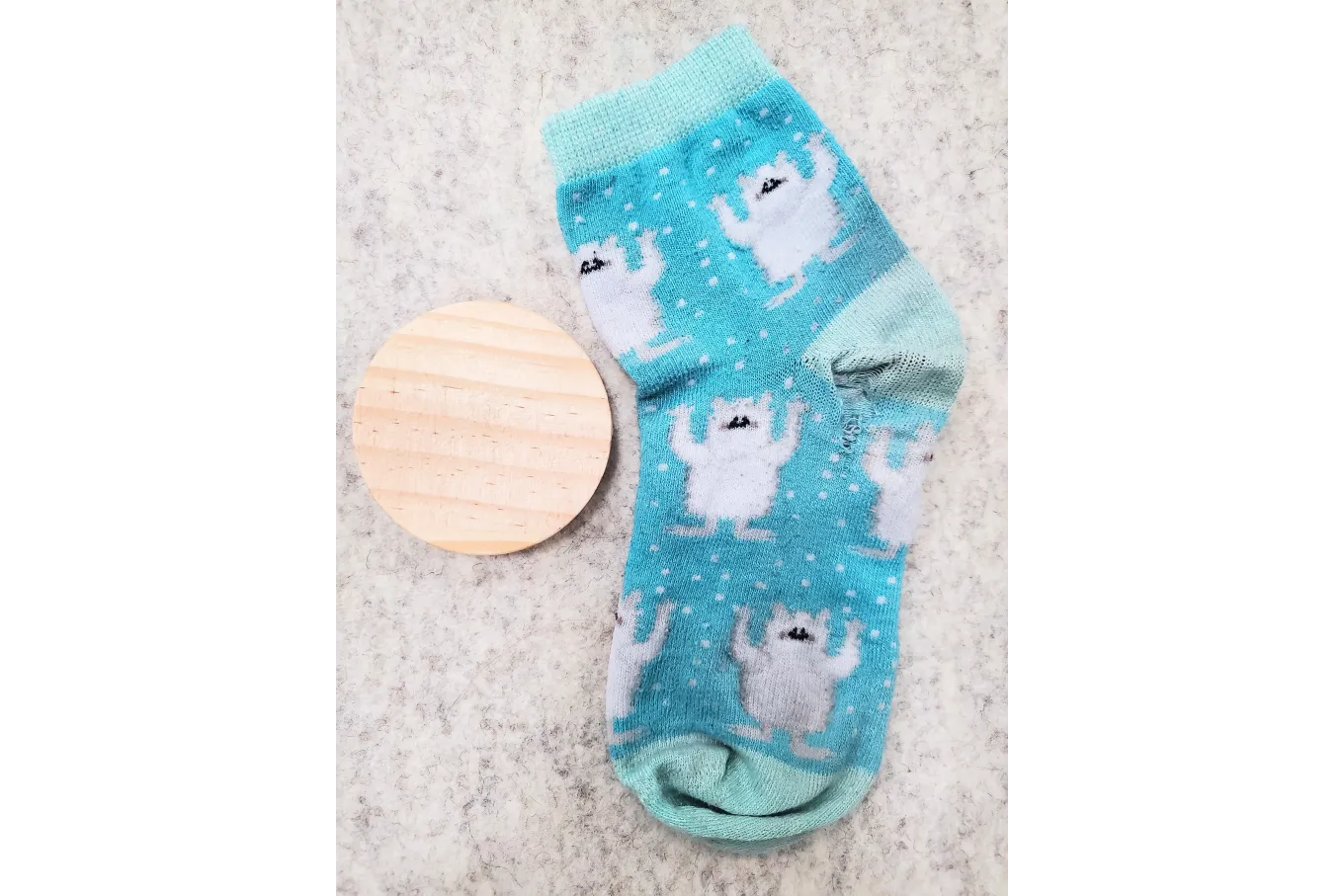 wooden disc next to blue sock with hole in heel