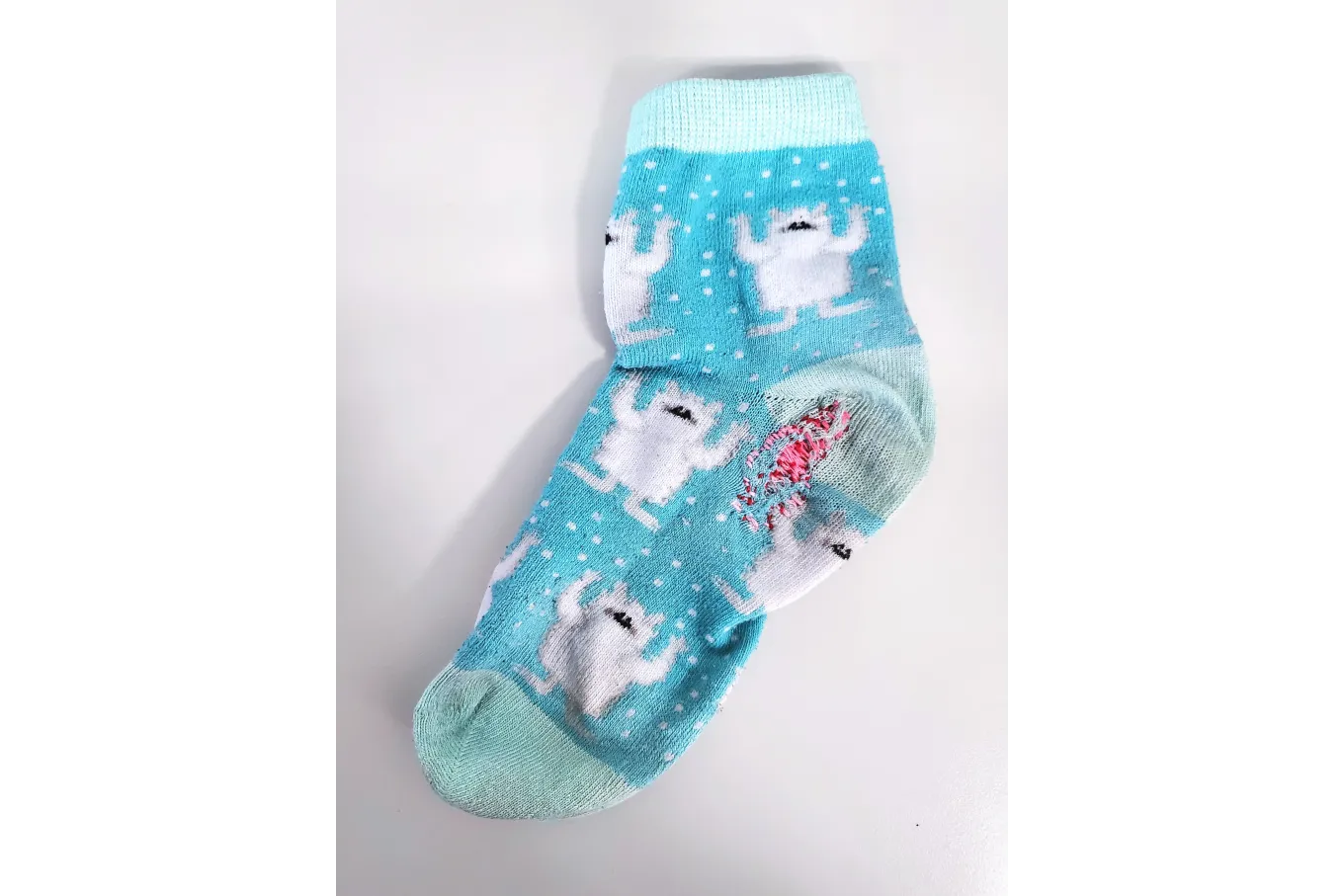 Blue polyester sock with yeti print have pink stitching in heel