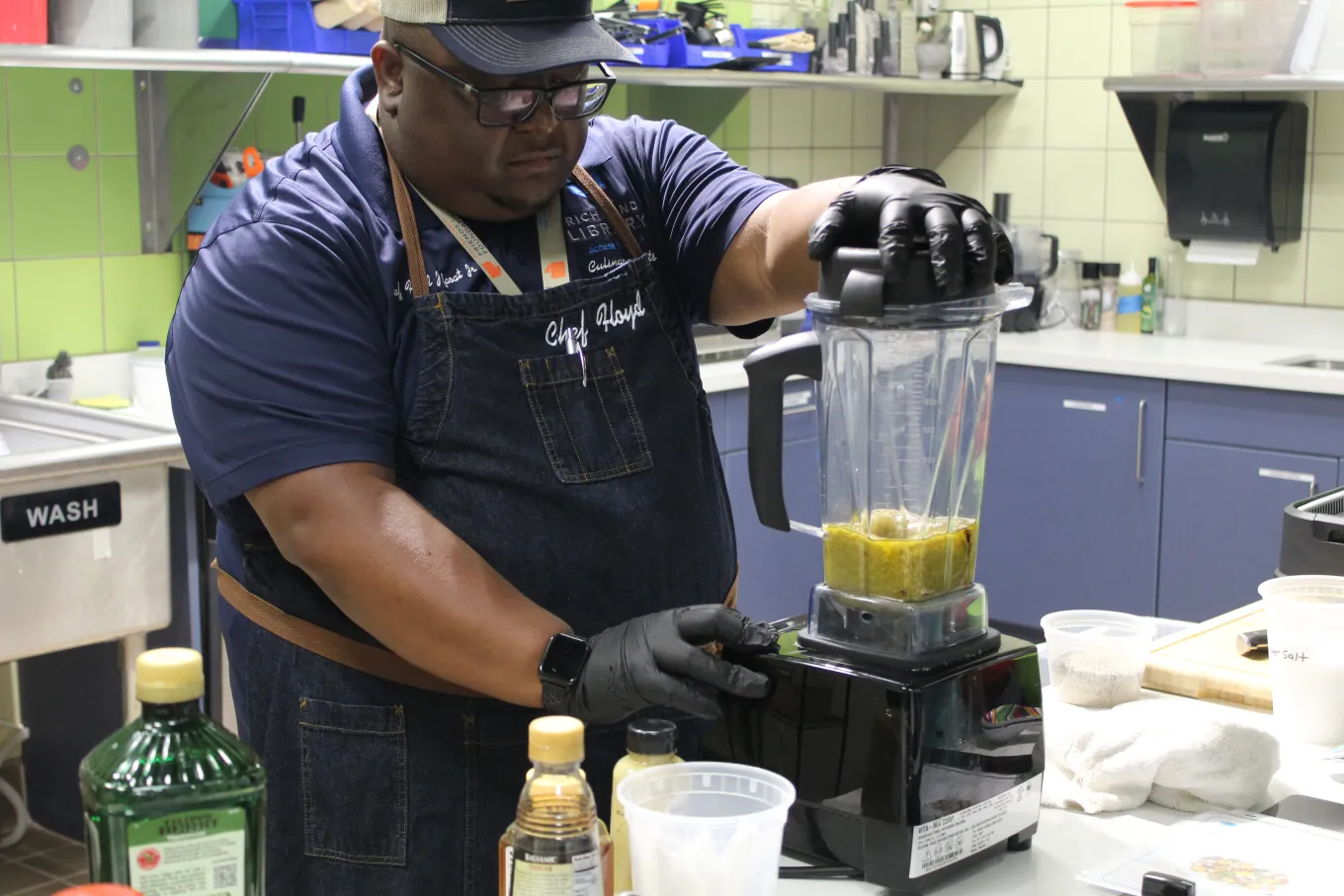 Chef preparing a sauce in a blender during a library cooking class.