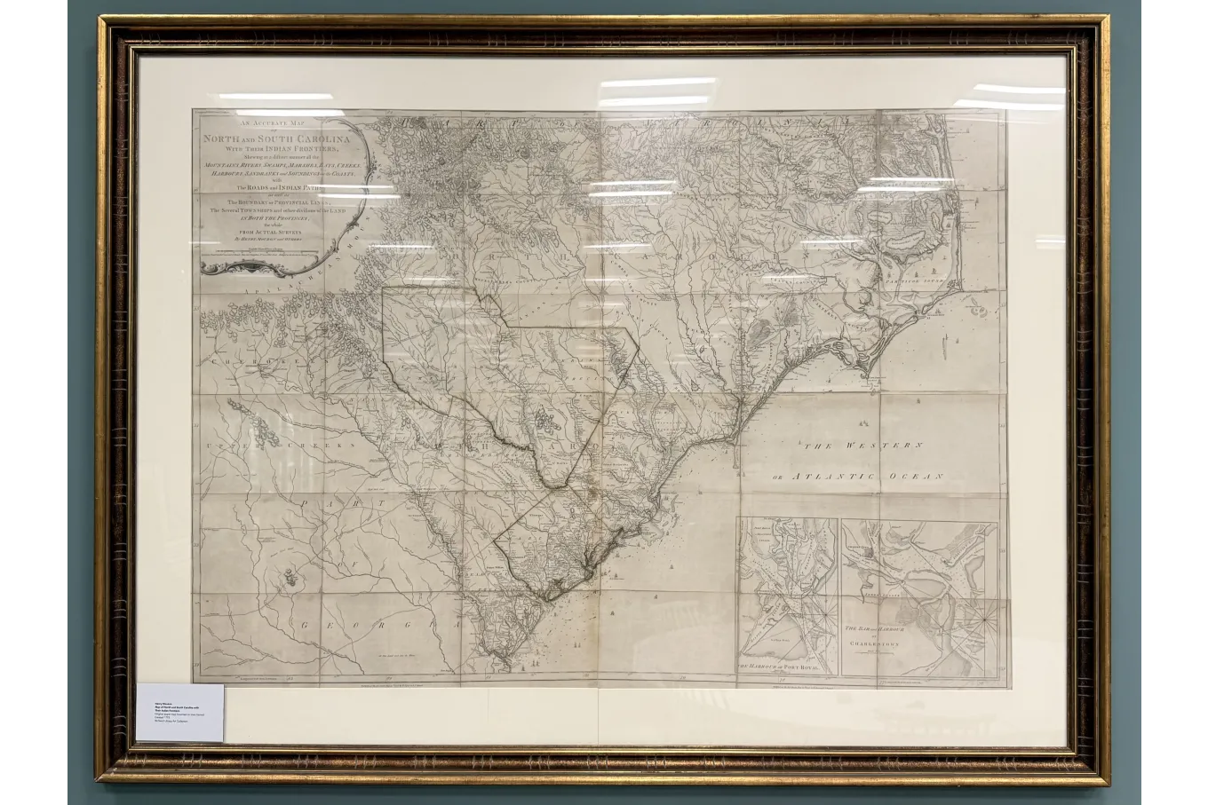 A large framed antique map depicts North and South Carolina with their Indian frontiers, rendered in fine, detailed linework. The map shows rivers, towns, roads, and coastal inlets, with the Atlantic Ocean labeled along the right side and Georgia to the southwest. Decorative cartouches and inset maps appear in the corners, and the aged paper and ornate frame emphasize its historical character.