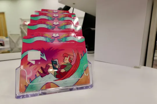 Library card and keychain card depicting Nimona, a character designed by ND Stevenson with the text "A Card with Character"