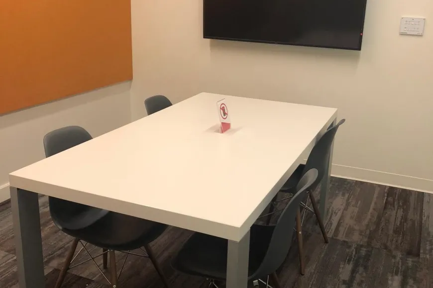 small study room with four chairs, one table and one flat panel monitor on wall