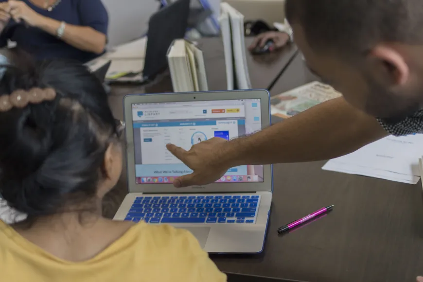 A man helps a woman use a computer