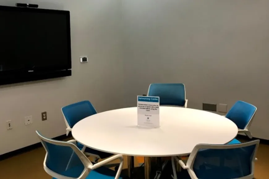 small room with table, 5 chairs and flat panel monitor on wall
