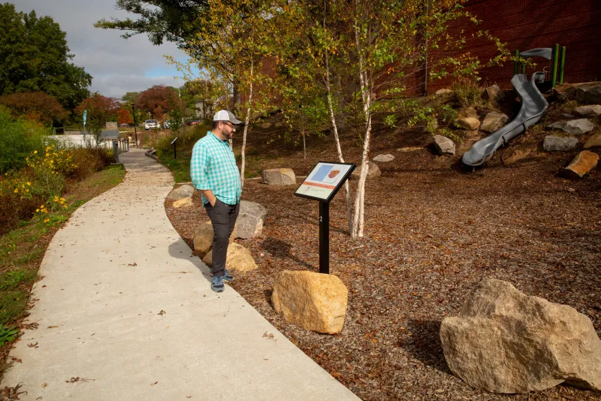 Man wearing a turquoise shirt reads the Richland Library StoryWalk at Hyatt Park in Columbia South Carolina.