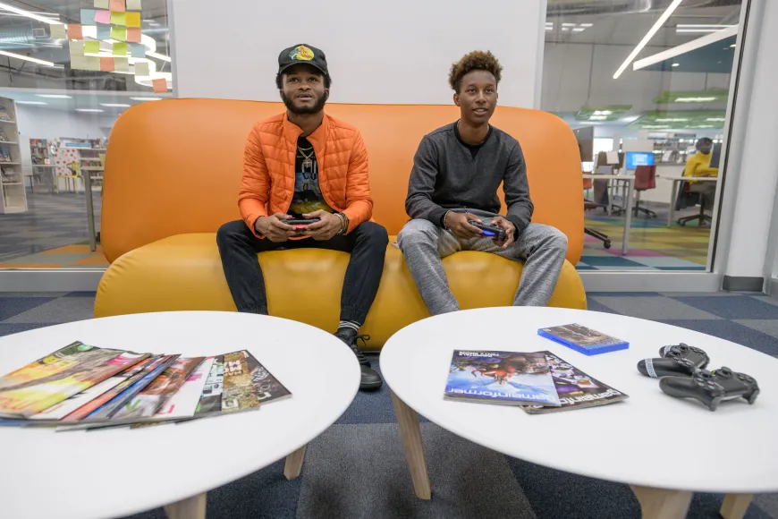 Two teens on couch playing video games