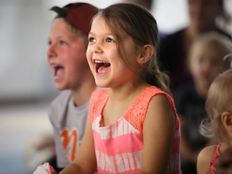 Two white children smile and laugh while listening to a story