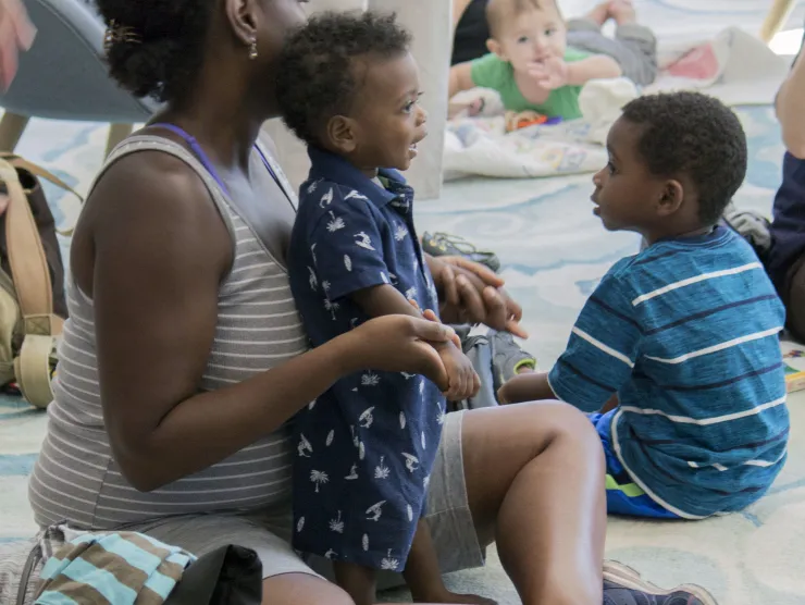 Black woman holds black child on her lap during storytime