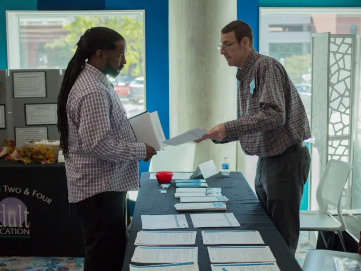 Staff member handing paper packet to guest