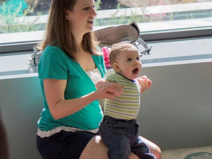 A mother and her infant sit in front of a window