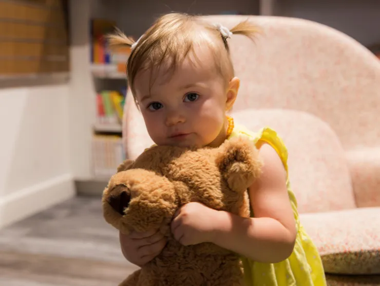 Baby with pigtails hugging a teddy bear.