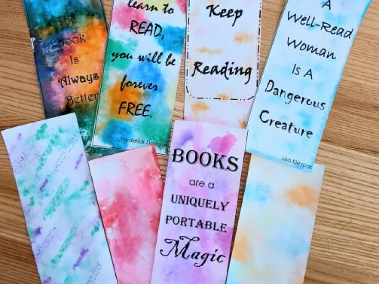 A display of colorful bookmarks with book-related quotes on them. They have been "tie-dyed" with markers.