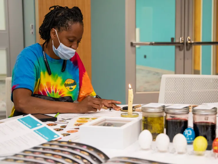 Black woman in colorful shirt crafts at Richland Library Main