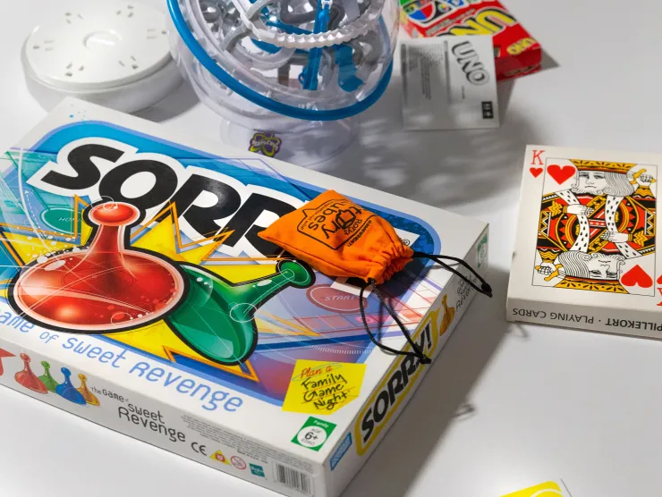 Various games like Sorry and a deck of cards sit on a white table