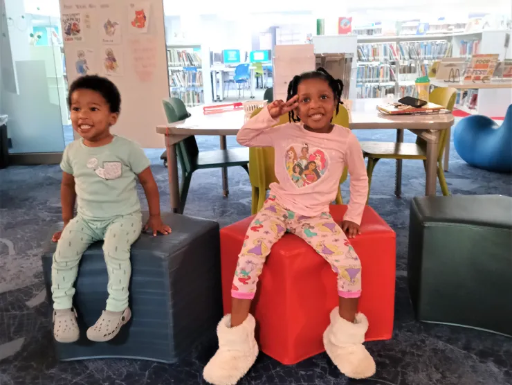 Two kids at the Northeast library children's room in their pajamas