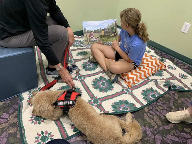 Little girl on the floor reading to a dog
