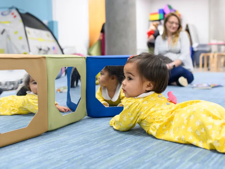 Baby playing on her belly on the floor in library story time room 
