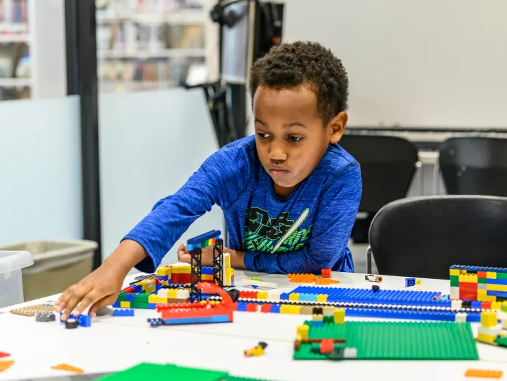 Boy creating with Legos sitting at a table 