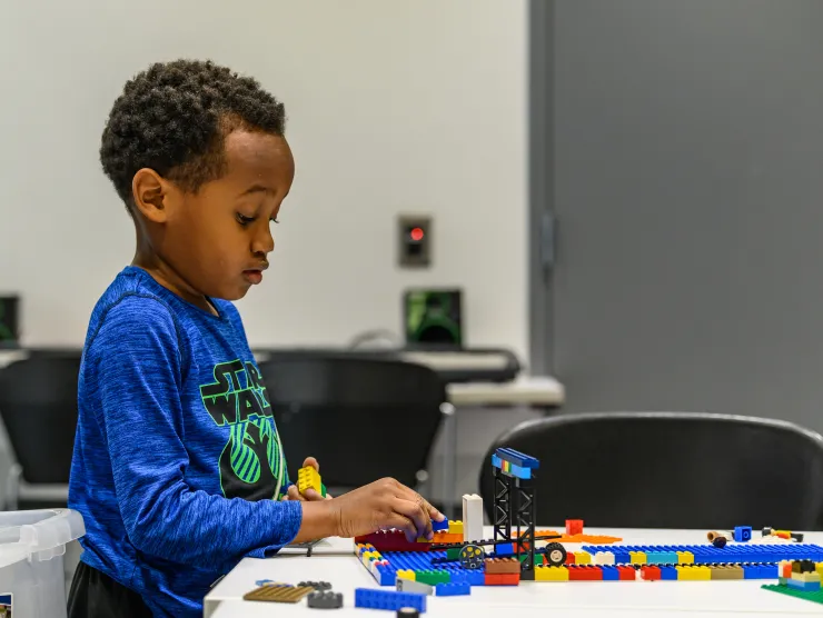 Boy creating with Legos sitting at a table 