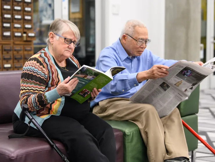 Older Adults reading on couch side view 