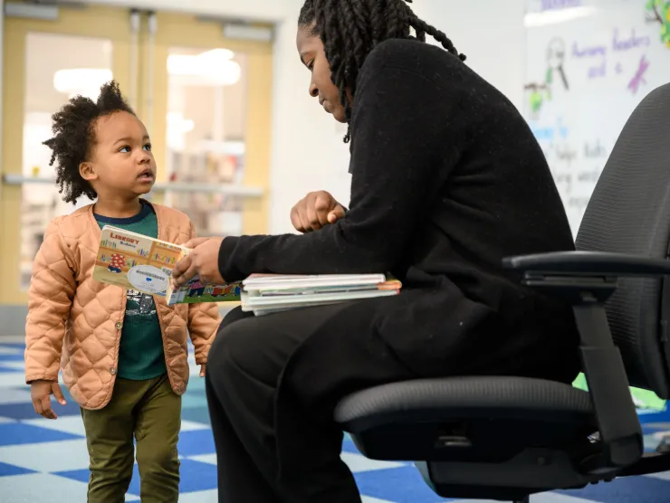 Library staff showing little boy a book one on one 