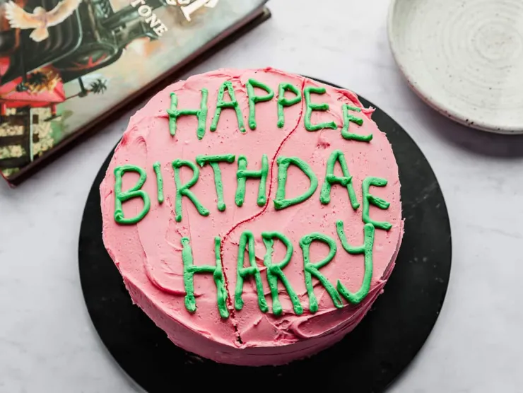 Birthday cake with pink that says "Happee Birthdae Harry" in green icing