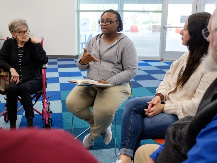 African American woman speaks in the center of a group of circled book club attendees